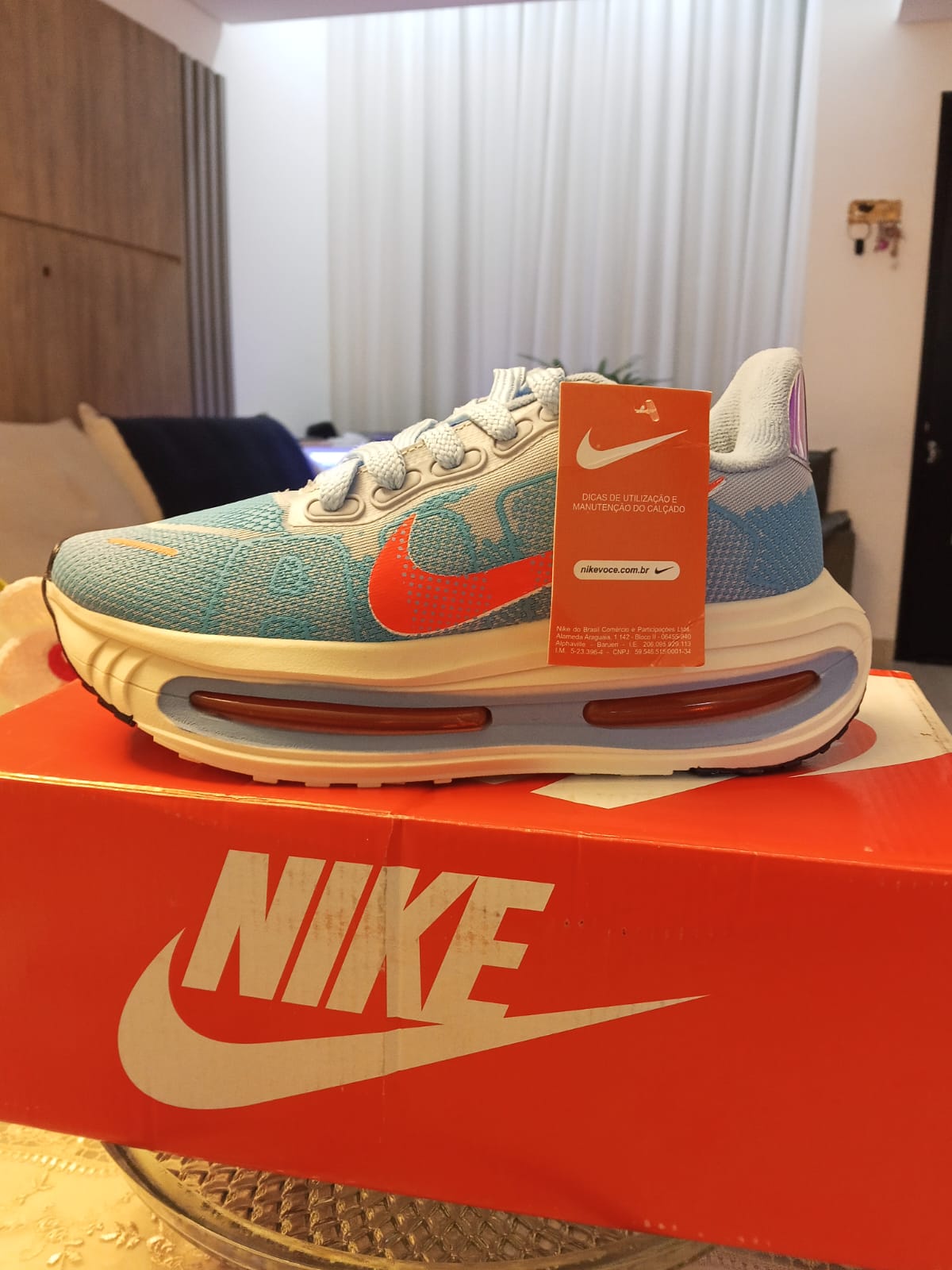 Tênis Nike azul e laranja sobre a caixa Nike